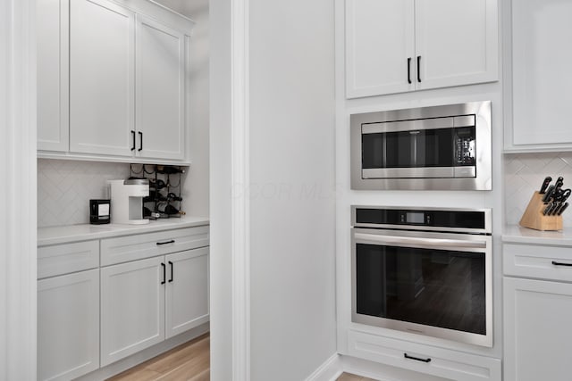 kitchen with light countertops, white cabinetry, backsplash, and stainless steel appliances