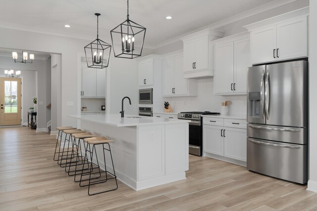 kitchen with a breakfast bar area, light countertops, a sink, a notable chandelier, and stainless steel appliances