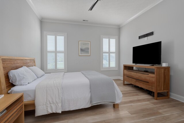 bedroom with a ceiling fan, visible vents, crown molding, baseboards, and light wood finished floors