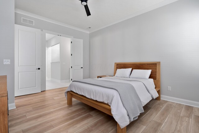 bedroom with visible vents, ornamental molding, light wood-style floors, and baseboards