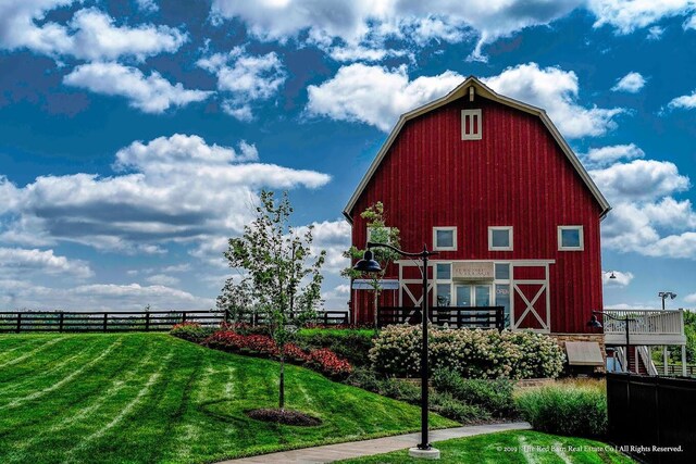 view of barn featuring fence and a yard