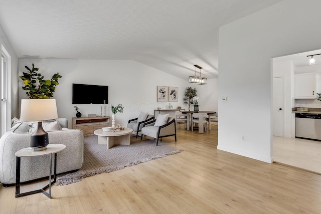 living area featuring lofted ceiling, light wood-style floors, and a chandelier