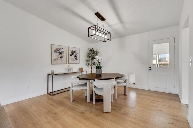 dining space with light wood-style flooring, vaulted ceiling, and baseboards