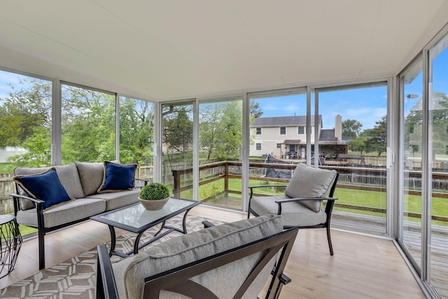sunroom featuring an outdoor hangout area, expansive windows, wood finished floors, and a wooden deck