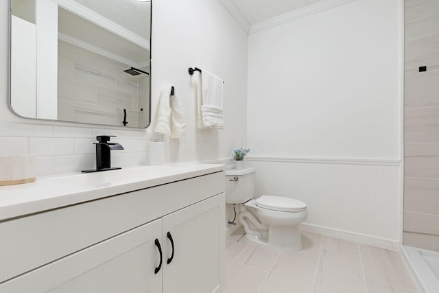 bathroom with ornamental molding, tiled shower, toilet, vanity, and a wainscoted wall