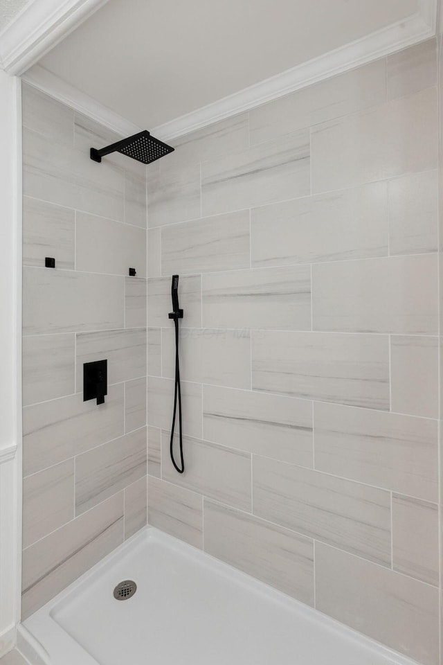 full bathroom featuring tiled shower and ornamental molding