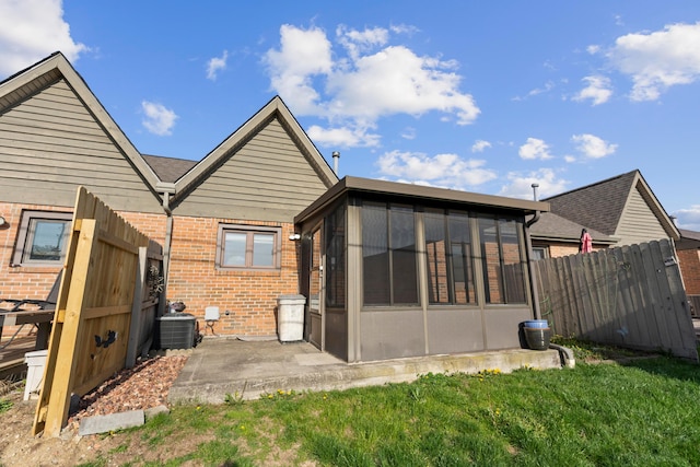 5796 Thada Ln, Columbus, OH 43229 - rear view of house featuring fence, a patio, cooling unit, brick siding, and a sunroom