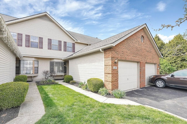 view of front of house with aphalt driveway, a shingled roof, brick siding, a front yard, and a garage