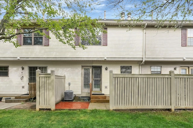 back of property with central air condition unit, a yard, and entry steps