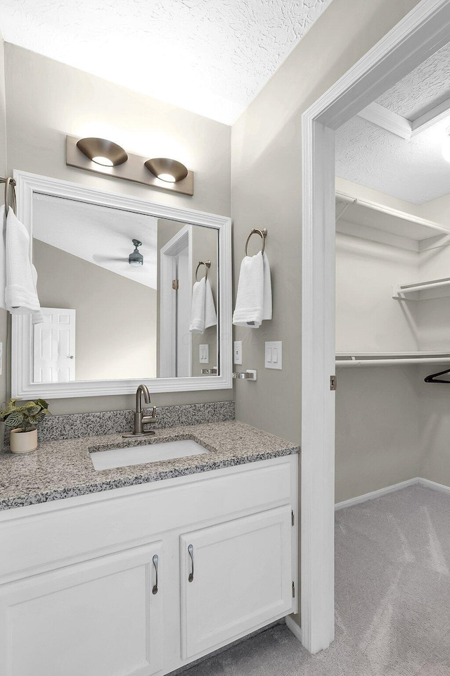 bathroom with a ceiling fan, vanity, and a textured ceiling