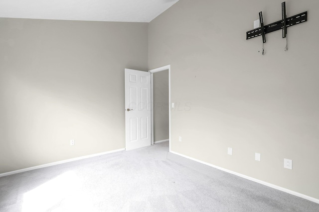 empty room with baseboards, lofted ceiling, and carpet