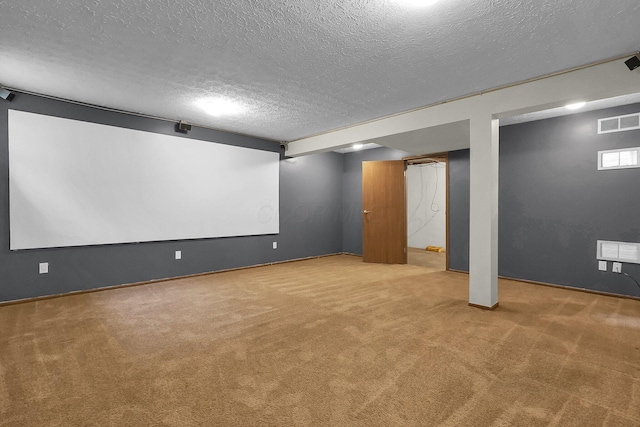finished basement with a textured ceiling, carpet floors, visible vents, and baseboards