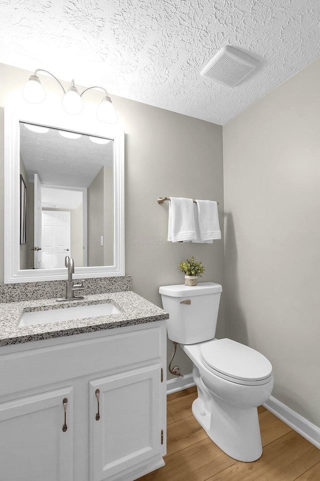 bathroom with wood finished floors, visible vents, toilet, and baseboards