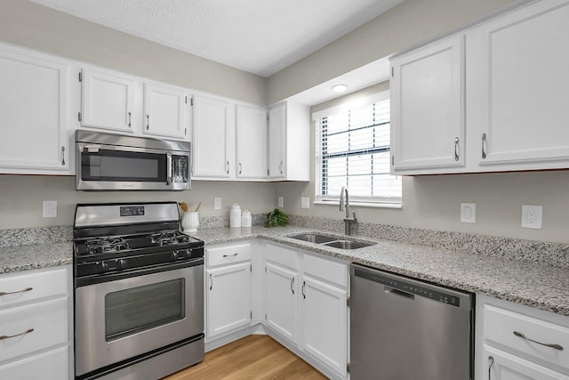 kitchen featuring appliances with stainless steel finishes, a sink, and white cabinetry