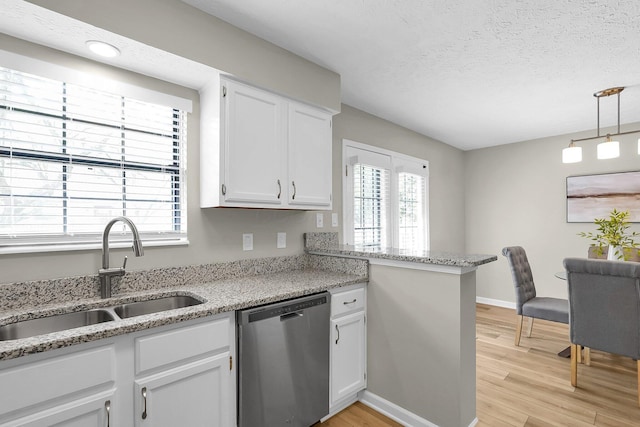 kitchen with stainless steel dishwasher, a sink, light wood-style flooring, a textured ceiling, and white cabinetry