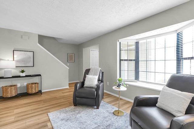 sitting room with wood finished floors, a textured ceiling, and baseboards