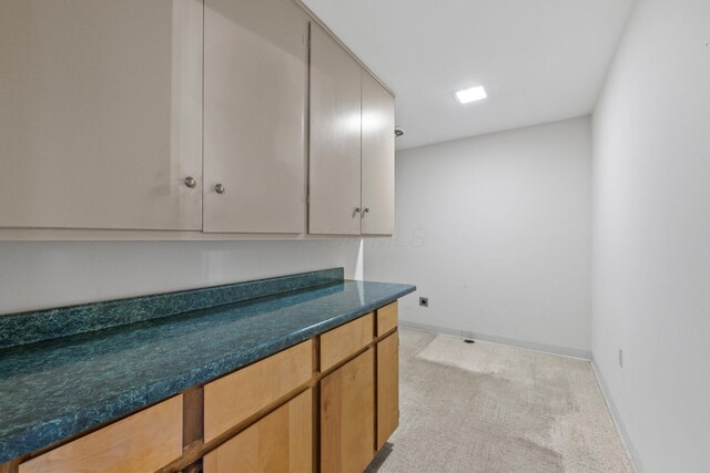 laundry room with baseboards and light colored carpet