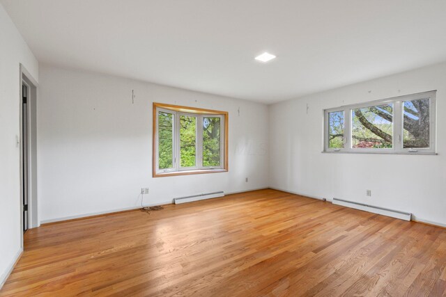 unfurnished room featuring baseboards, baseboard heating, a baseboard heating unit, and light wood finished floors