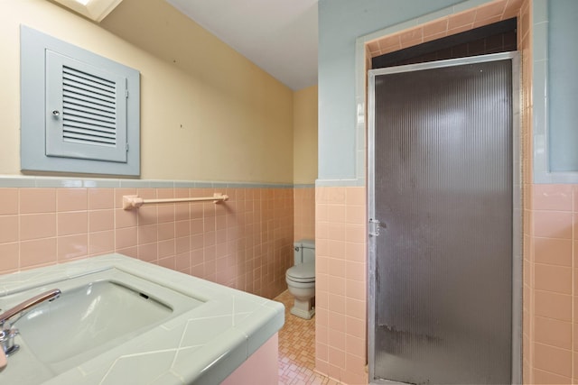 bathroom with toilet, tile walls, wainscoting, and a stall shower