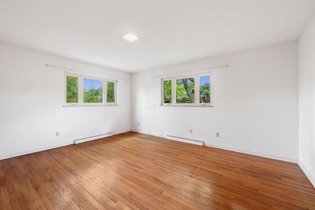 unfurnished room featuring light wood-style floors, a wealth of natural light, and a baseboard radiator