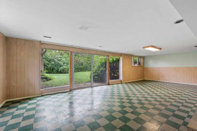 unfurnished room featuring visible vents, wood walls, and baseboards