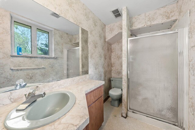 bathroom with vanity, a stall shower, toilet, and visible vents
