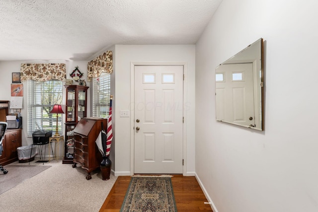entryway with baseboards, a textured ceiling, and wood finished floors