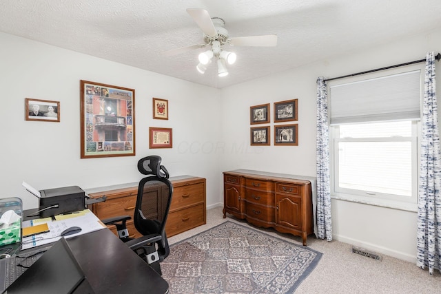 office space with light carpet, a ceiling fan, a textured ceiling, and visible vents