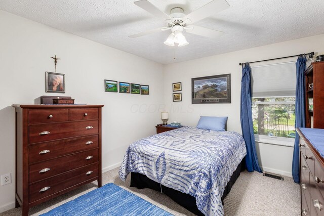 bedroom with ceiling fan, a textured ceiling, and light colored carpet