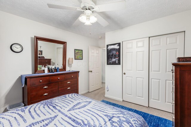 carpeted bedroom with a closet, a textured ceiling, ceiling fan, and baseboards