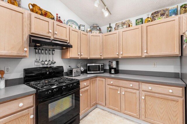 kitchen with stainless steel microwave, under cabinet range hood, light brown cabinetry, and black gas range oven