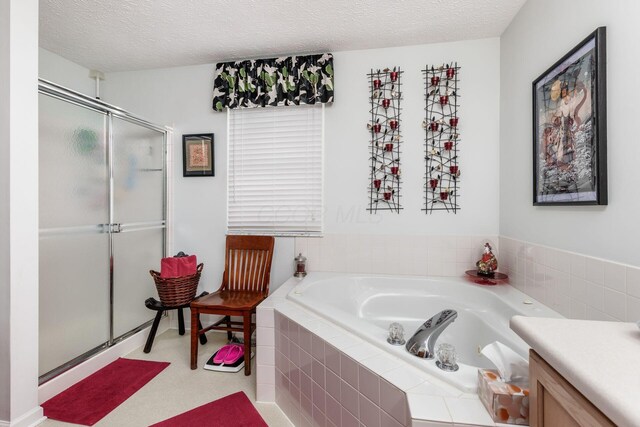 full bath with a textured ceiling, vanity, a stall shower, and a bath