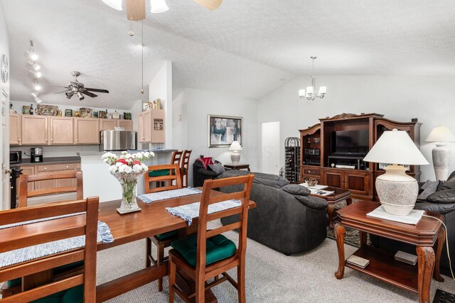 dining area featuring a textured ceiling, lofted ceiling, light carpet, and ceiling fan with notable chandelier