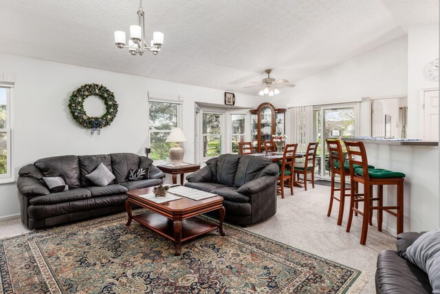 carpeted living area featuring a textured ceiling, plenty of natural light, lofted ceiling, and ceiling fan with notable chandelier