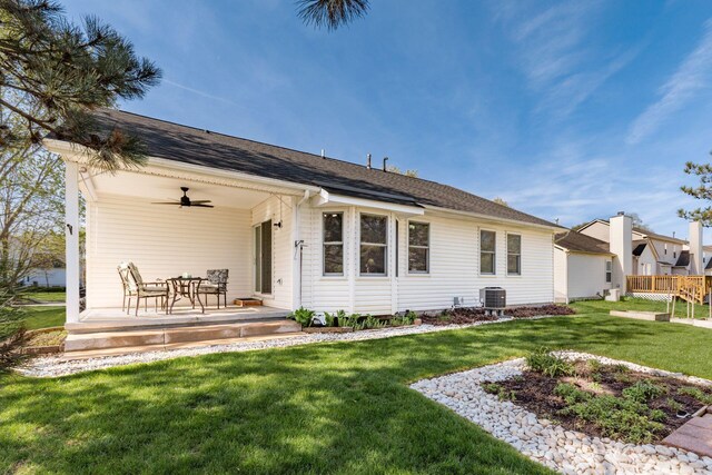 back of house with central air condition unit, a lawn, and ceiling fan