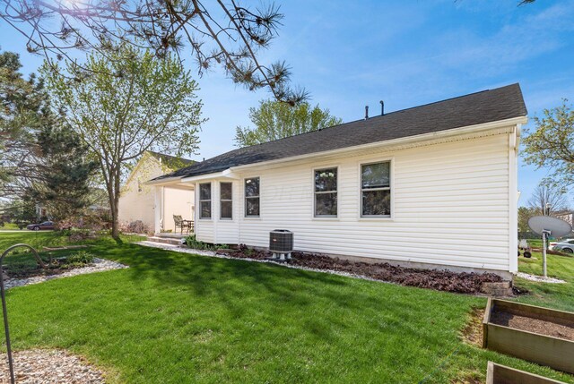 back of property with central AC unit, a yard, and a vegetable garden