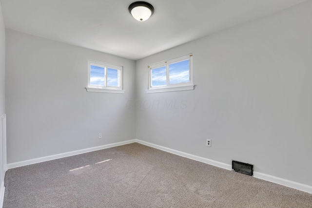 spare room with carpet flooring, visible vents, and baseboards