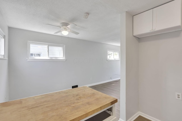interior space with a textured ceiling, a ceiling fan, and baseboards