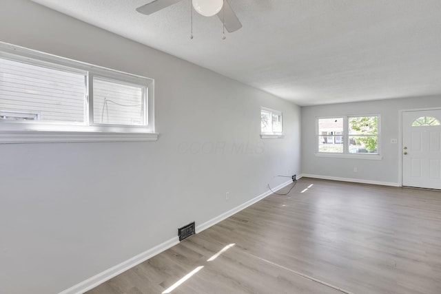 spare room with wood finished floors, ceiling fan, visible vents, and baseboards