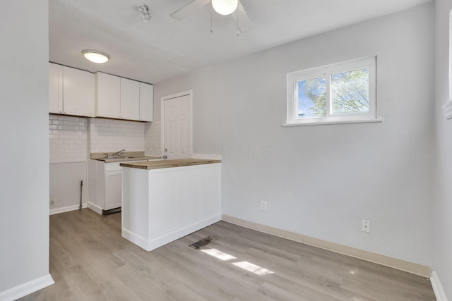 kitchen with ceiling fan, light wood-type flooring, white cabinets, and backsplash