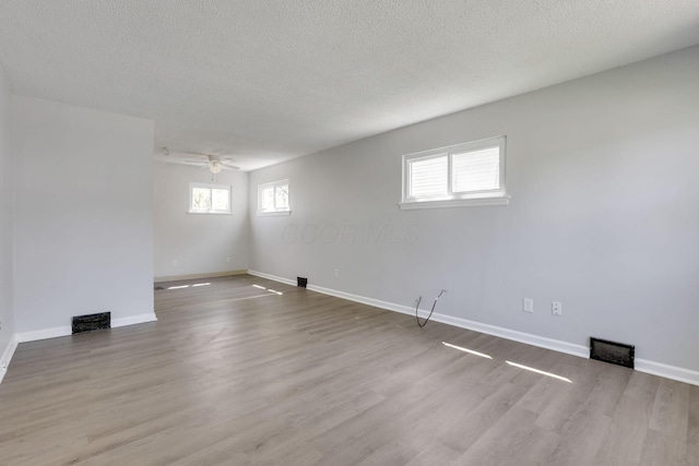 basement featuring wood finished floors, visible vents, a ceiling fan, and baseboards