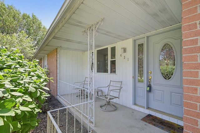 entrance to property with covered porch and brick siding