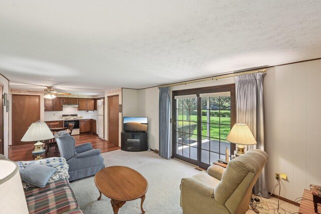 living room with a textured ceiling, ceiling fan, and light carpet
