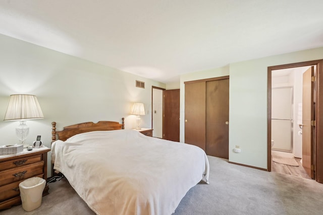 bedroom featuring visible vents, light carpet, and ensuite bath