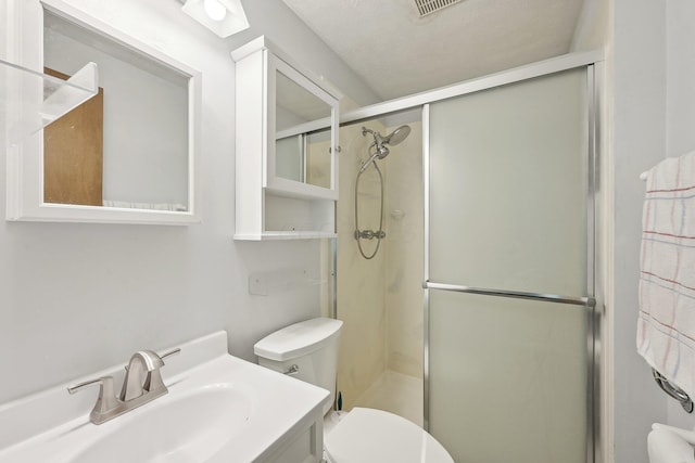bathroom with toilet, a shower stall, and vanity
