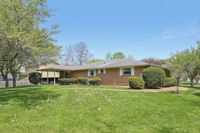back of property with a lawn, fence, and brick siding
