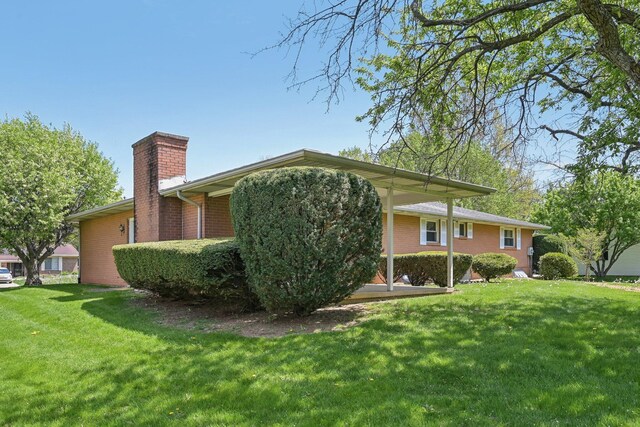 view of home's exterior featuring brick siding, a lawn, and a chimney