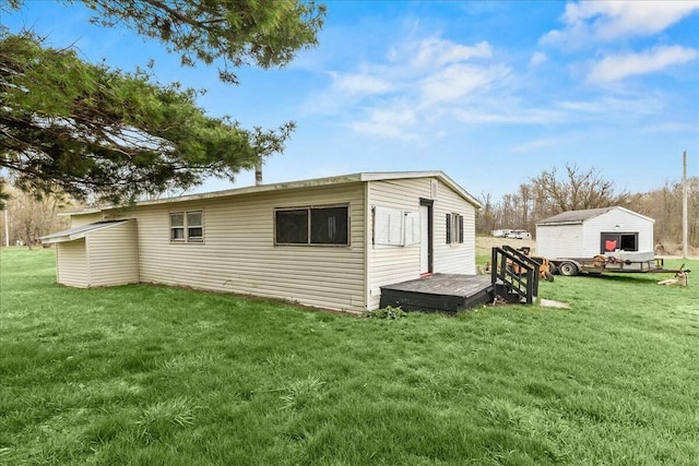 back of house featuring an outdoor structure, a wooden deck, and a yard