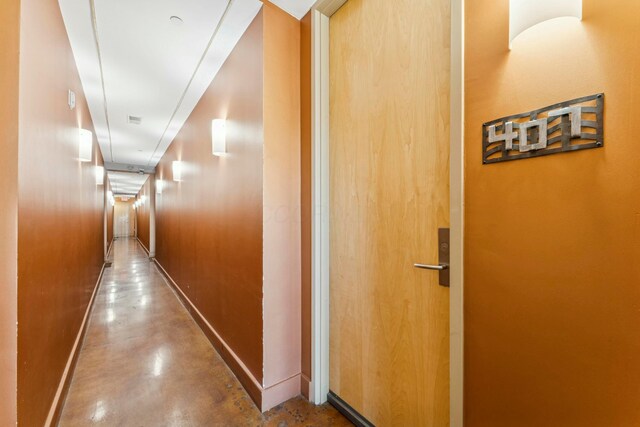 hall with baseboards and concrete flooring