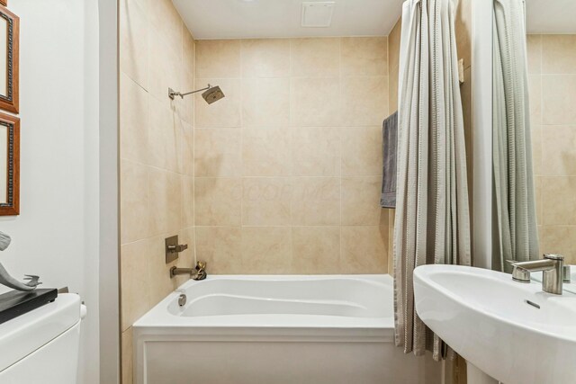 bathroom featuring shower / bath combo with shower curtain, toilet, and a sink